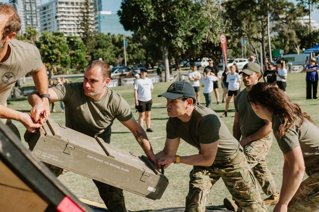 people during the competition, helping each other carrying a big wooden box